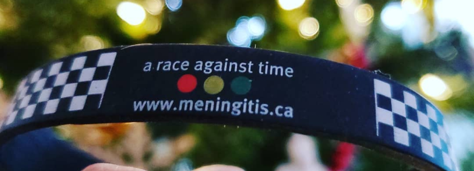 Hand holding a wristband that says " a race against time, www.meningitis.ca".