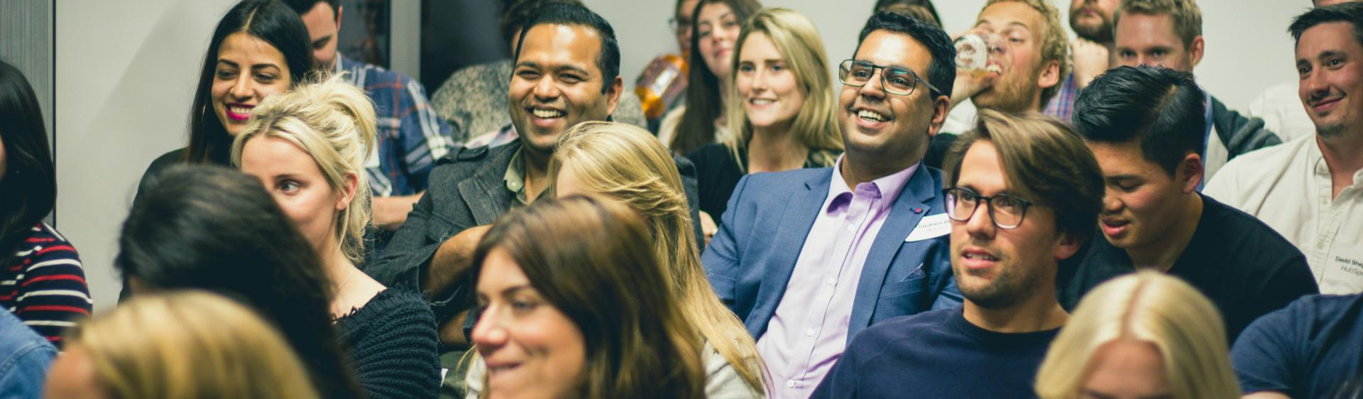 people sitting down at a conference and smiling. 
