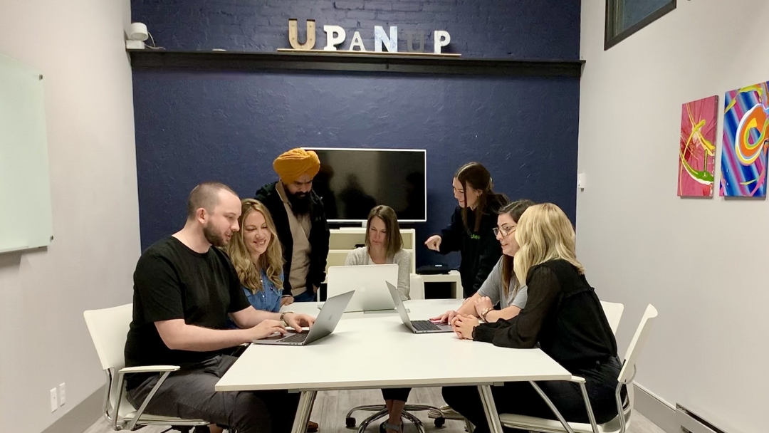 Group of people working at a table with laptops. 