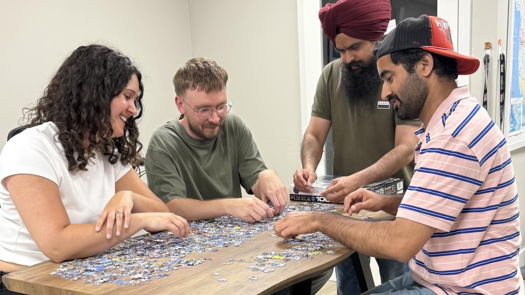 Nicole, Carter, Hargurpreet, Gurpreet from Upanup doing a puzzle at a table.