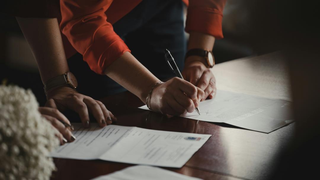 Two people signing documents on a table