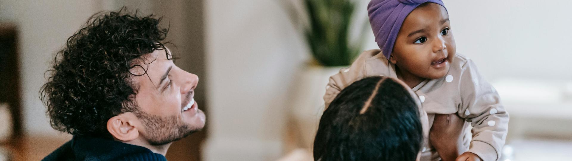 Anonymous black mother embracing adorable daughter, near father