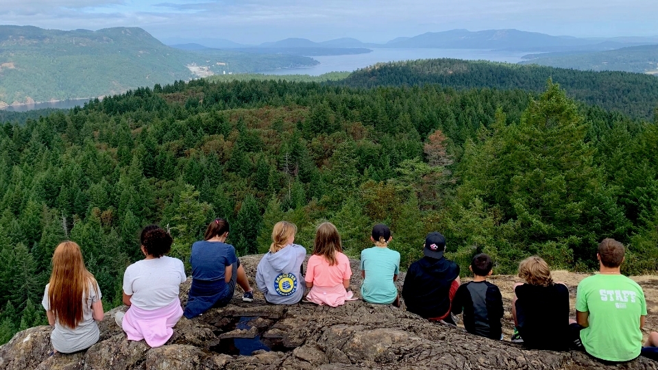 Kids sitting on a rock on a lookout. 