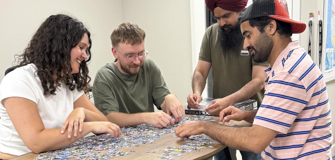Nicole, Carter, Hargurpreet, Gurpreet from Upanup doing a puzzle at a table.