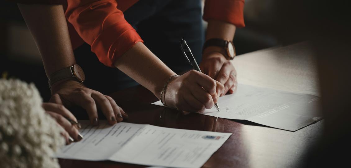 Two people signing documents on a table