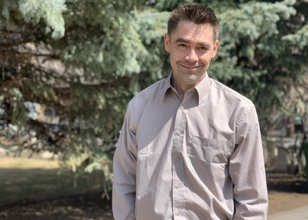 Cory standing in front of trees, looking at the camera smiling