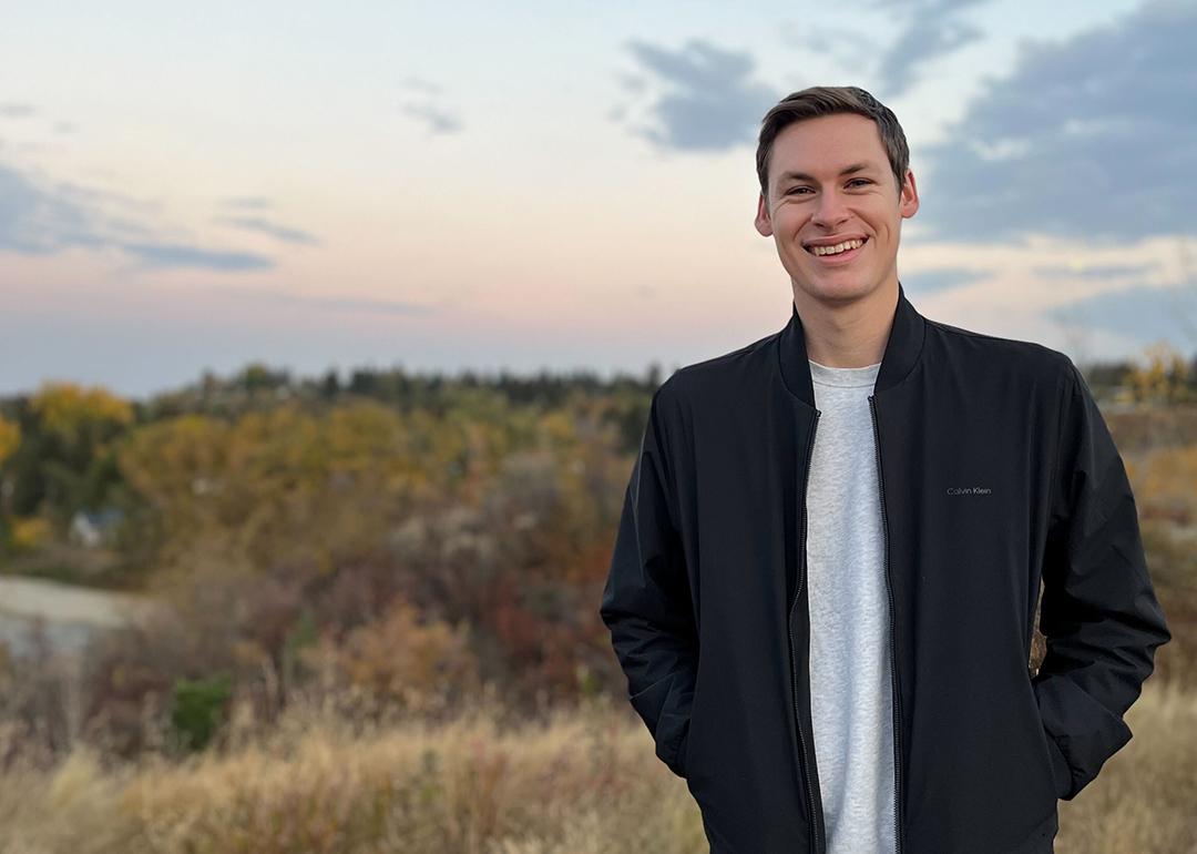 A man standing outside at sunset in a dark blue jacket